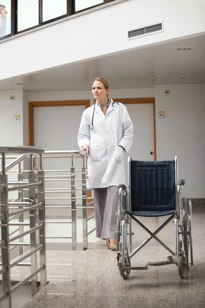 Στοχαστικό γιατρός που στέκεται δίπλα σε μια αναπηρική καρέκλα — Φωτογραφία Αρχείου