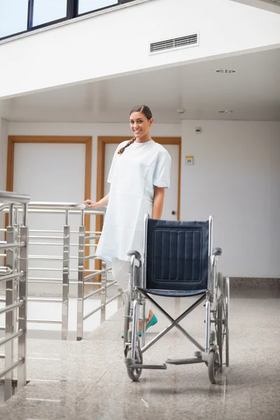 Smiling patient standing next to a wheelchair — Stock Photo, Image