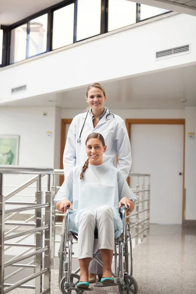 Paciente sentado en una silla de ruedas junto a un médico — Foto de Stock