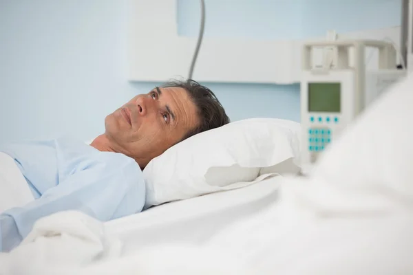 Düşünceli hastanın tıbbi bir yatakta yatarken — Stok fotoğraf
