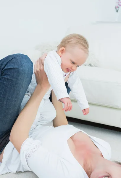 Mãe deitada enquanto segura um bebê — Fotografia de Stock