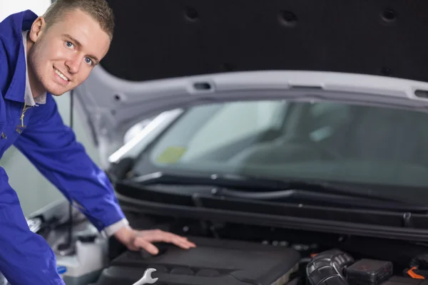 Mechanic camera kijken terwijl leunend op een auto — Stockfoto