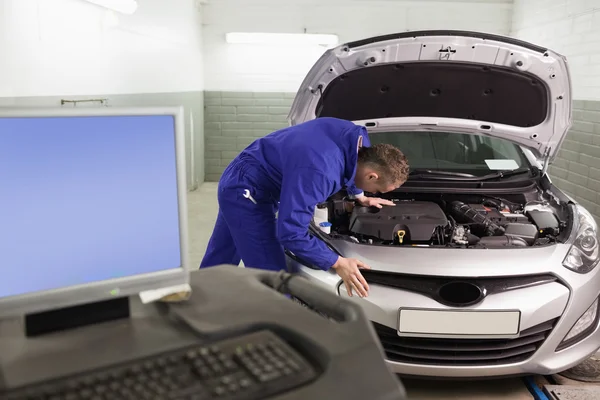 Mecânico reparar um carro ao lado de um computador — Fotografia de Stock