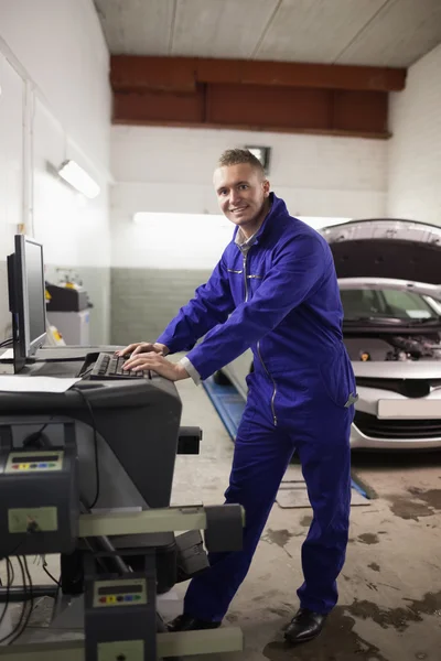 Mechanic using a computer while smiling — Stock Photo, Image