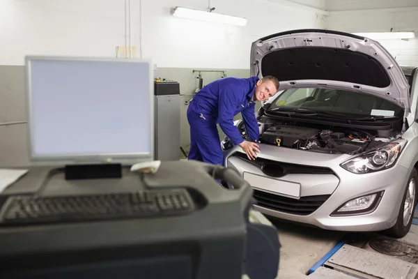 Leende mekaniker undersöker en bilmotor — Stockfoto