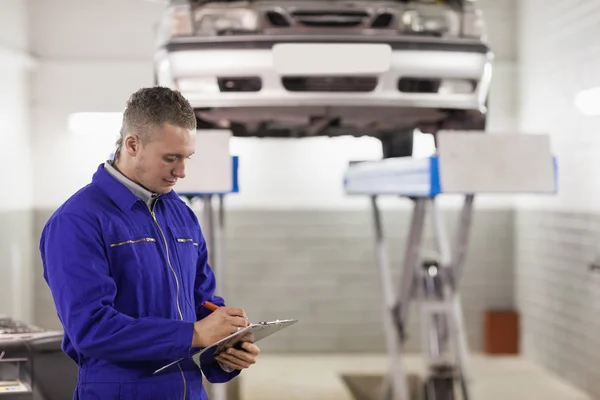 Mechanic holding a clipboard while looking at it — Stock Photo, Image