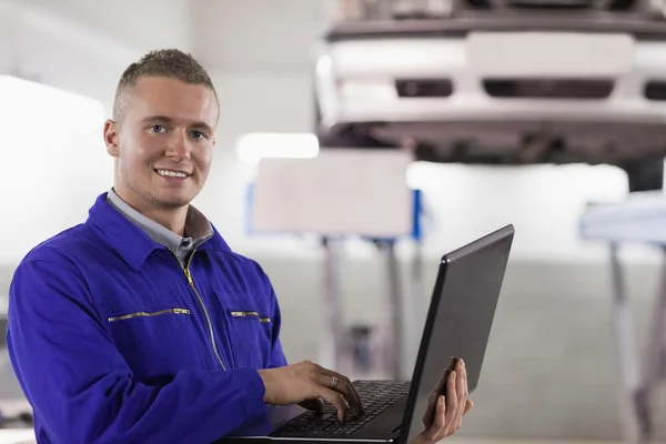 Mecânico sorridente usando um laptop — Fotografia de Stock