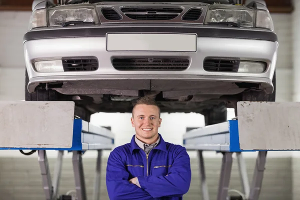 Mechanic met gekruiste onder een auto armen — Stockfoto