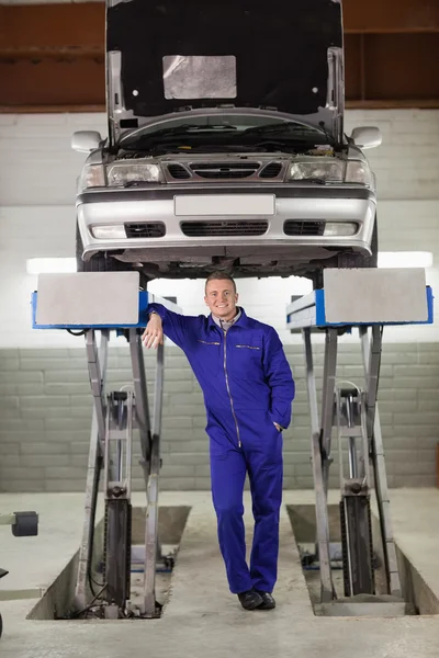Uśmiechający się mechanik stojący pod samochód — Zdjęcie stockowe