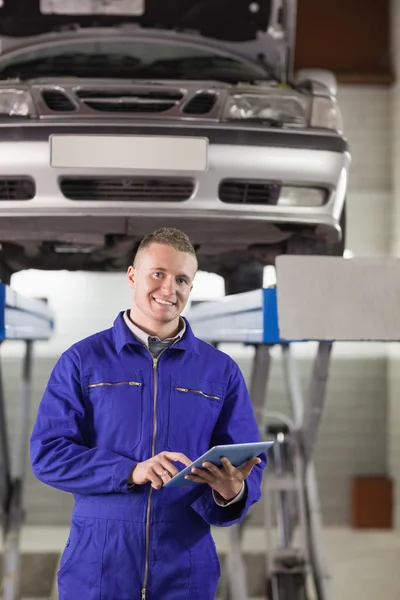 Mechanic aanraken van een tablet-computer terwijl de camera kijken — Stockfoto