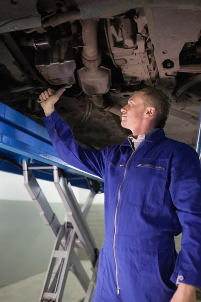 Mechaniker repariert mit einem Schraubenschlüssel die Unterseite eines Autos — Stockfoto