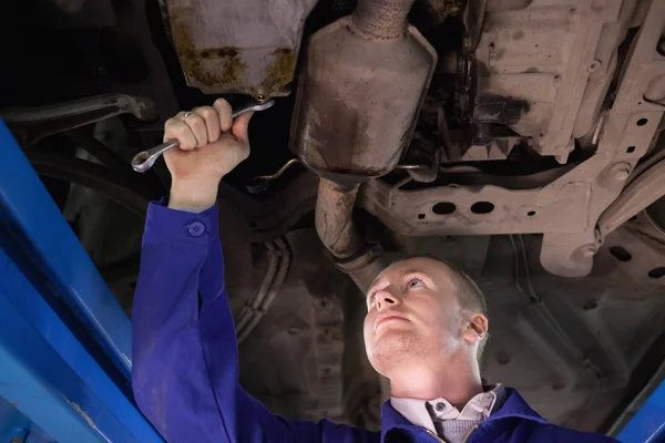 Concentrated mechanic looking at the below of a car — Stock Photo, Image