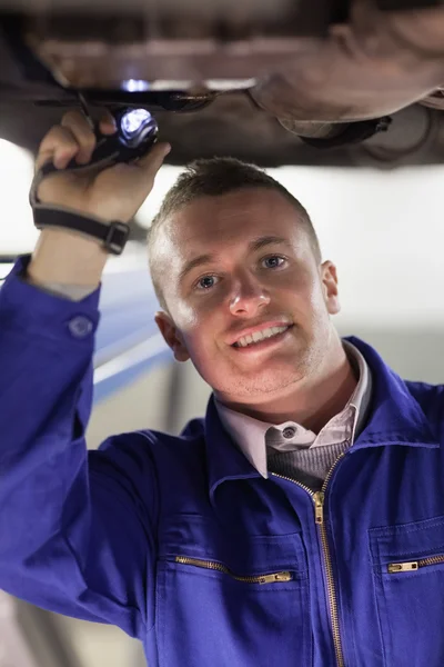 Mecánico que ilumina la parte inferior de un coche — Foto de Stock