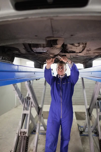 Meccanico in piedi durante la riparazione del sotto di una macchina — Foto Stock
