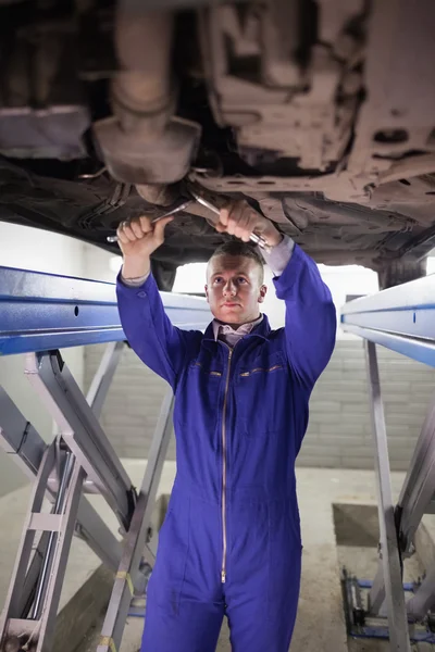 Concentrated mechanic repairing a car with spanners — Stock Photo, Image