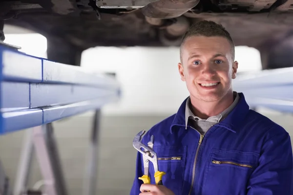 Smiling mechanic holding an adjustable pliers — Stock Photo, Image