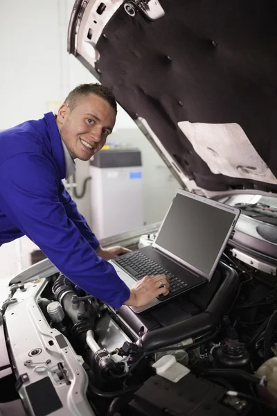 Mecánico sonriente trabajando en una computadora — Foto de Stock