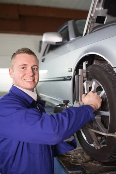 Smiling mechanic repairing a car wheel — Stock Photo, Image