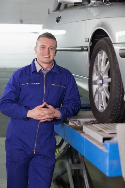 Front view of a smiling mechanic next to a car — Stock Photo, Image