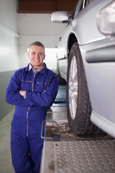 Front view of a mechanic smiling next to a car — Stock Photo, Image