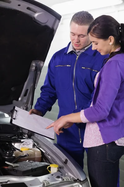 Frau blickt auf Klemmbrett neben Auto — Stockfoto