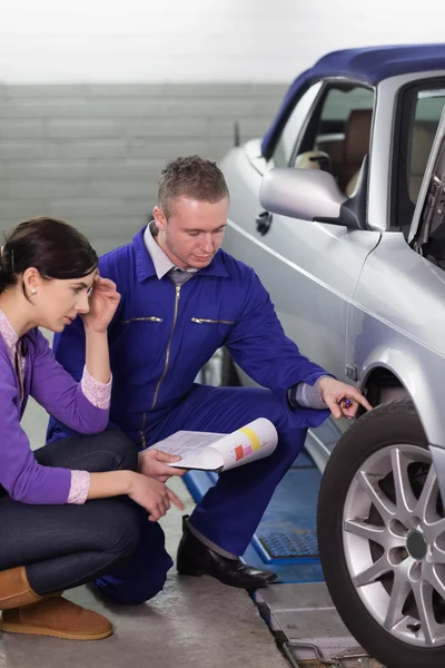 Mechanic touching the car wheel while looking at it — Stock Photo, Image
