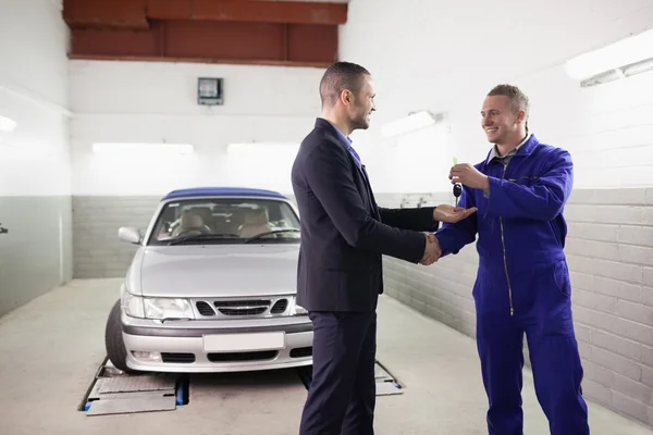 Mechanische geven auto-toets terwijl het schudden de hand aan een client — Stockfoto