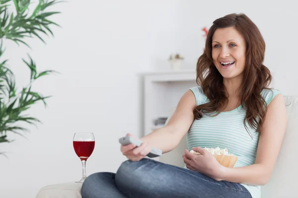 Frau lächelt, während sie eine Fernbedienung drückt — Stockfoto