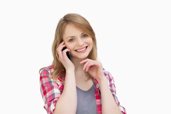 Woman holding a mobile phone while looking at camera — Stock Photo, Image