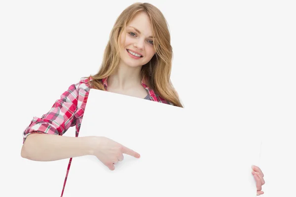 Femme regardant la caméra tout en montrant un tableau blanc — Photo