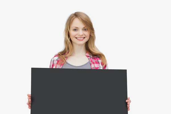 Woman looking at camera while holding a black board — Stock Photo, Image
