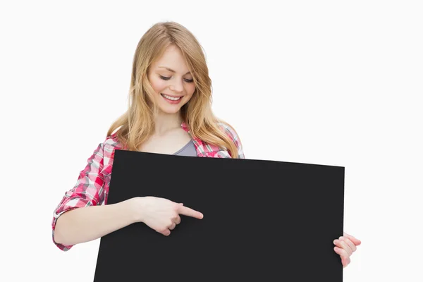 Sorrindo mulher mostrando uma placa preta com o dedo — Fotografia de Stock