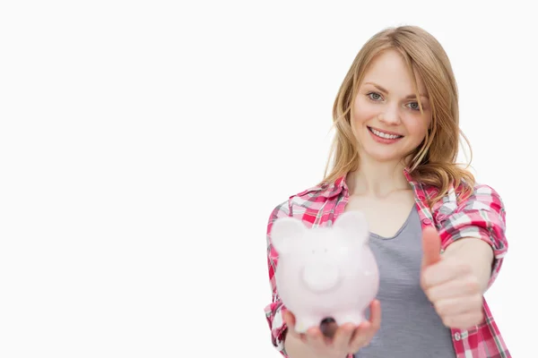 Vrouw met duim omhoog terwijl een piggy bank — Stockfoto