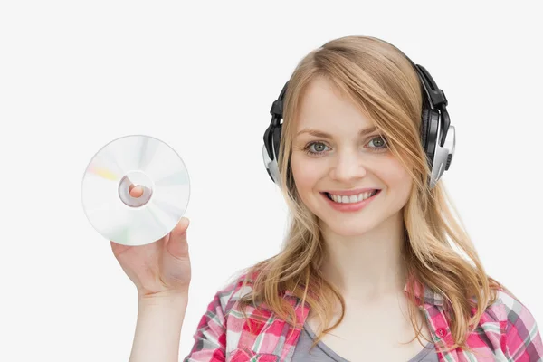 Frau hält eine CD in der Hand, während sie Kopfhörer trägt — Stockfoto