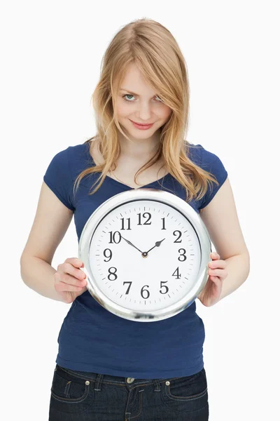 Woman looking at camera while holding a clock — Stock Photo, Image