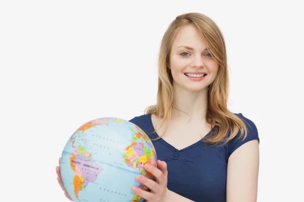 Frau lächelt, während sie einen Globus in der Hand hält — Stockfoto
