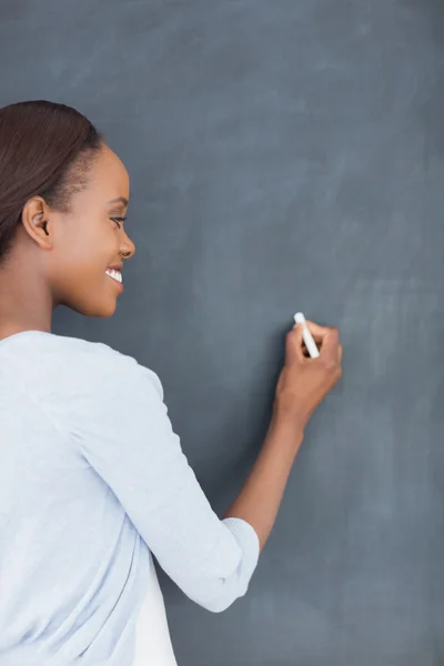 Black woman writing on a blackboard — Stock Photo, Image