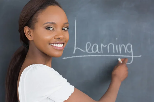 Teacher showing the blackboard while smiling — Stock Photo, Image