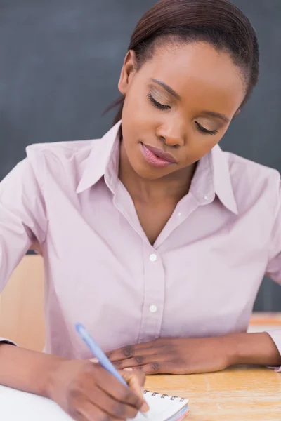 Zwarte leraar schrijven op een notitieblok — Stockfoto