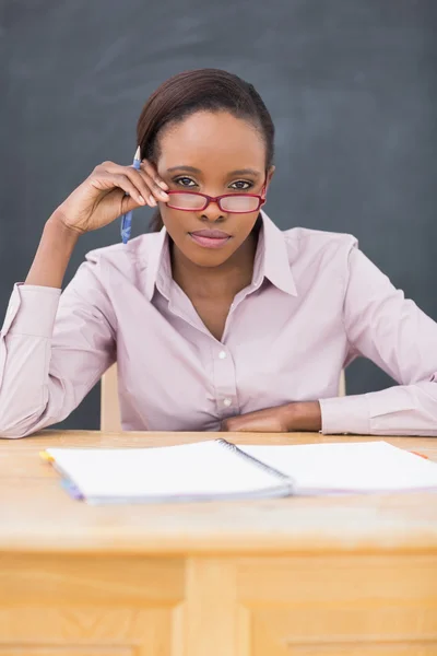 Вчитель сидить за столом, торкаючись її окулярів — стокове фото