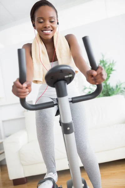 Black woman doing exercise bike while listening music — Stock Photo, Image