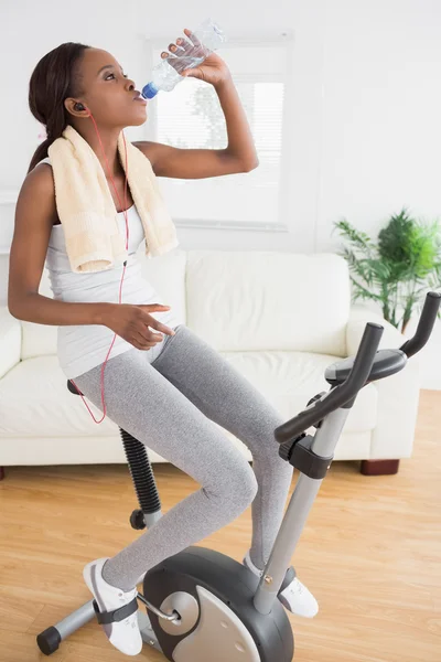 Mujer negra haciendo bicicleta de ejercicio mientras bebe — Foto de Stock