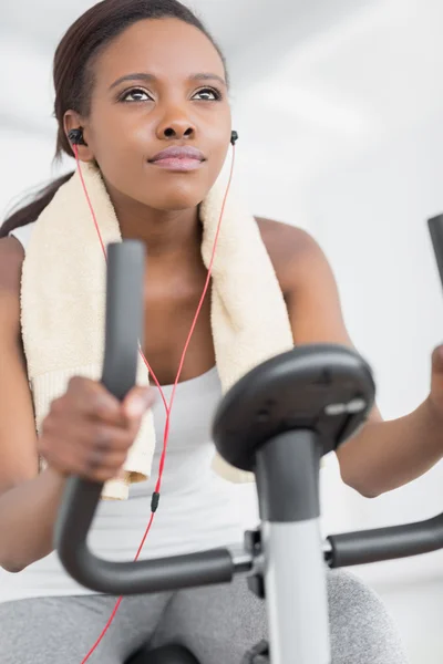 Müzik dinleme sırasında egzersiz bisikleti yapmaya konsantre kadın — Stok fotoğraf