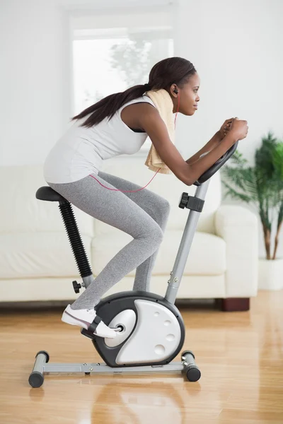 Side view of a concentrated black woman doing exercise bike — Stock Photo, Image