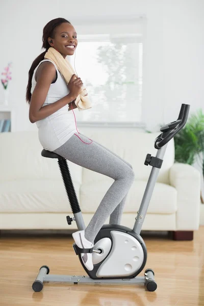 Black woman on an exercise bike smiling — Stock Photo, Image