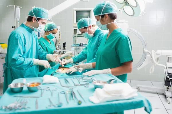 Vista lateral de un equipo quirúrgico operando a un paciente — Foto de Stock
