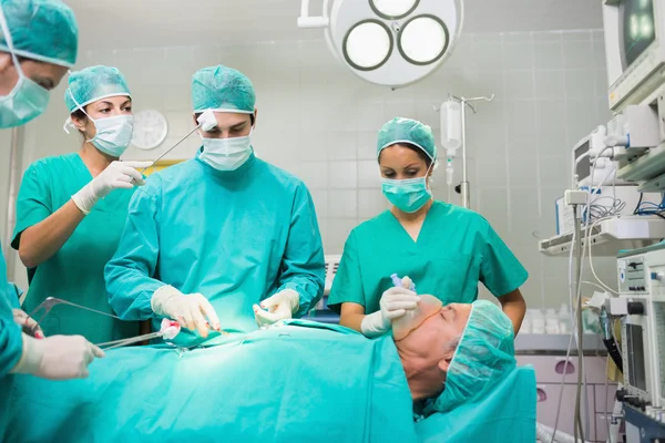 护士干燥额头上的一个集中的外科医生 — 图库照片