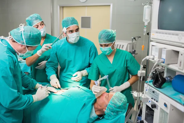 Krankenschwester trocknet Stirn eines Chirurgen neben einer Patientin — Stockfoto