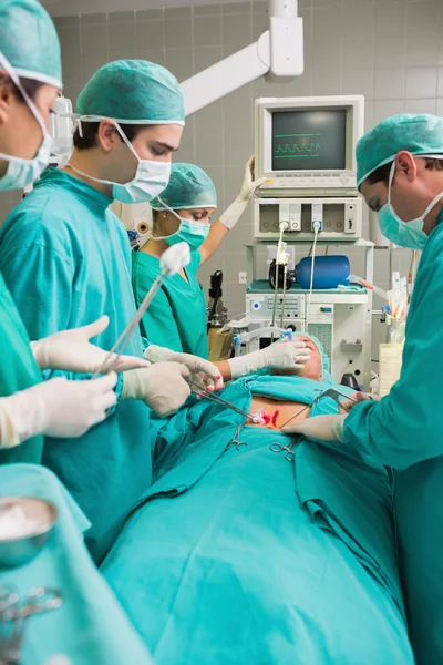 Visão lateral de uma equipe cirúrgica ao lado de um paciente — Fotografia de Stock