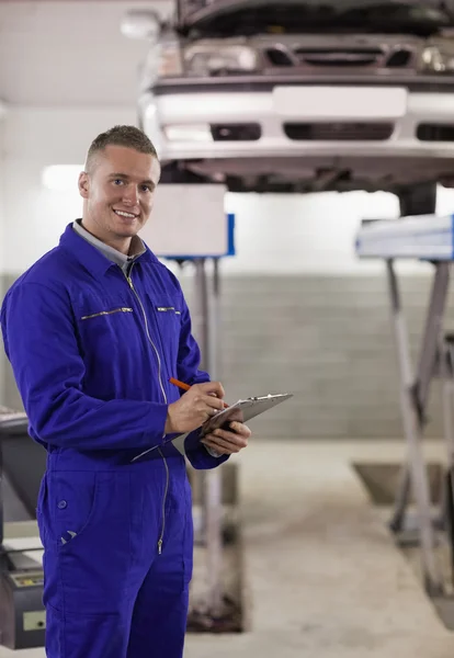 Smiling mechanic writing on a clipboard Royalty Free Stock Photos